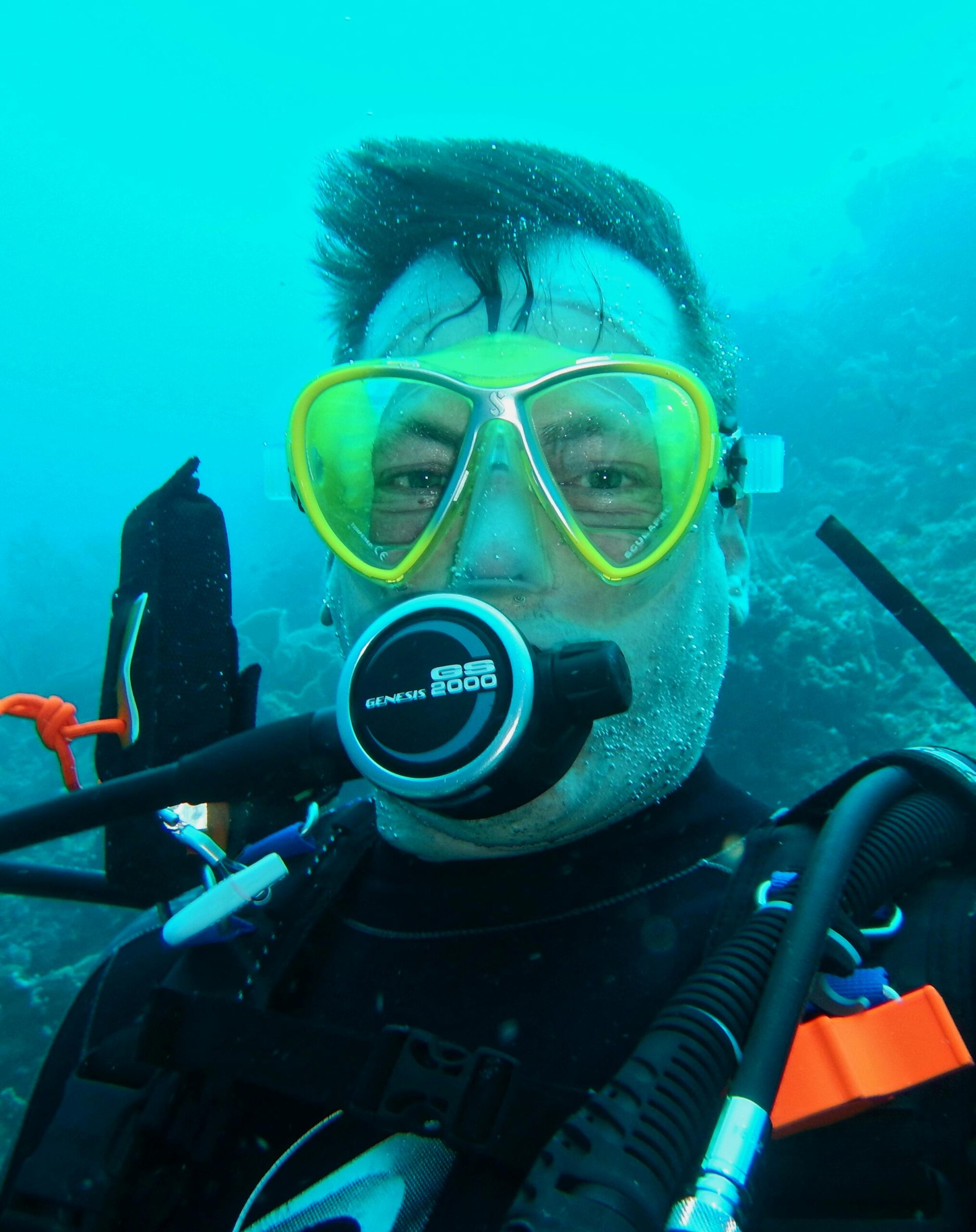 Close-up of a scuba diver with yellow goggles underwater in Indonesia's diverse marine ecosystem.